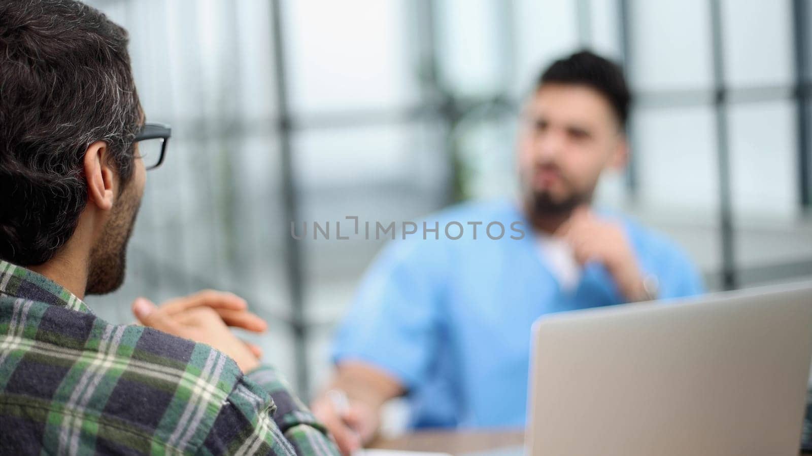 male doctor consulting patient filling form at consultation.