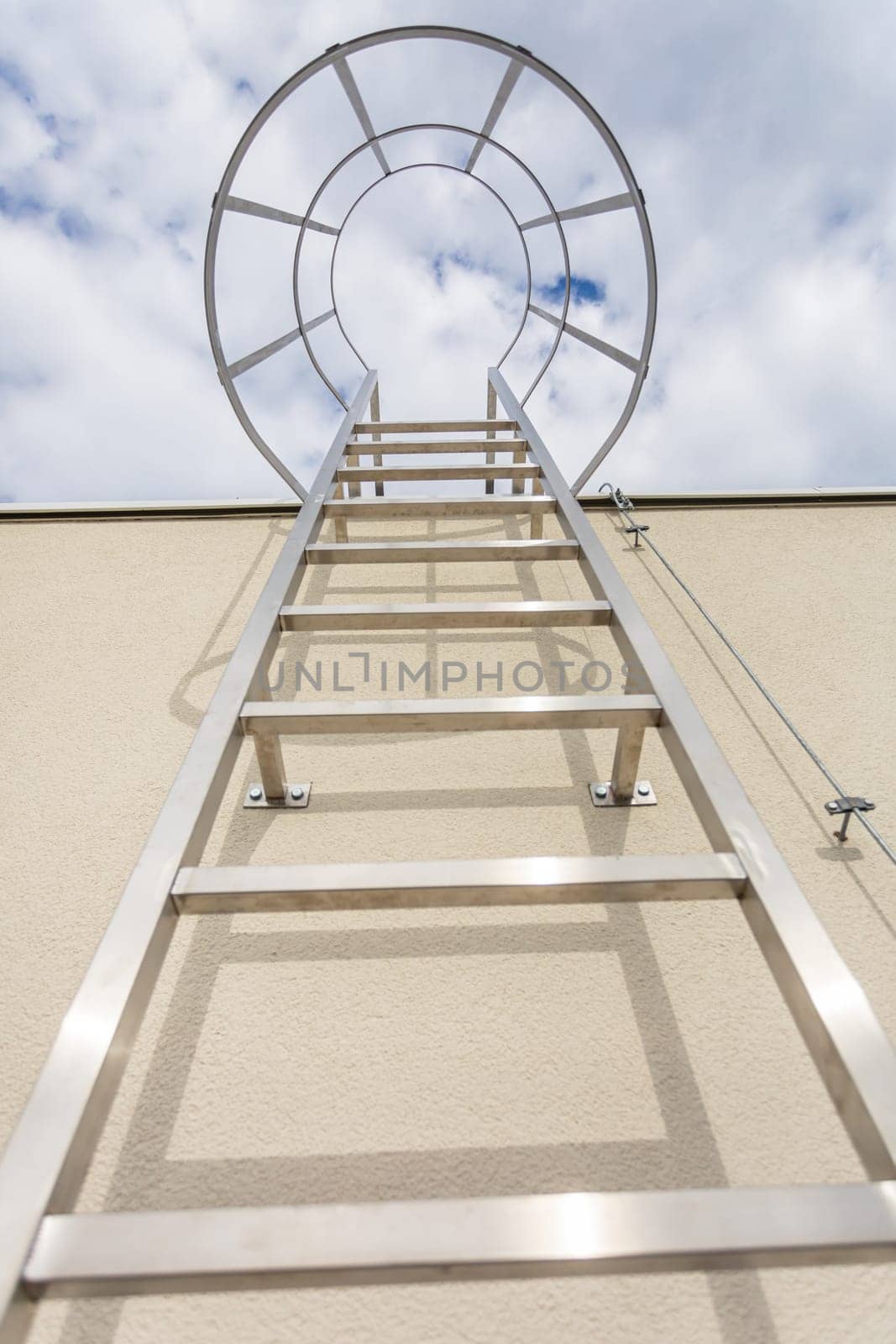 Bottom view of the stainless steel ladder mounted on the building facade. Technical access on the outside of the building to the higher part of the roof.
