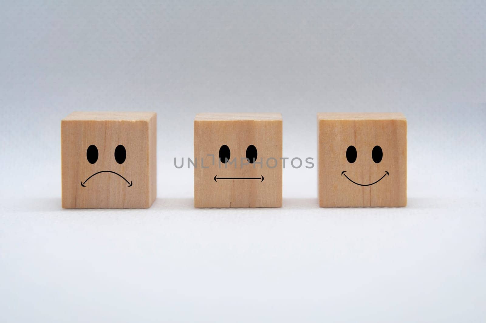 Sad, neutral and happy emoticon faces on wooden cubes with white background cover. Customer feedback, satisfaction and evaluation concept.