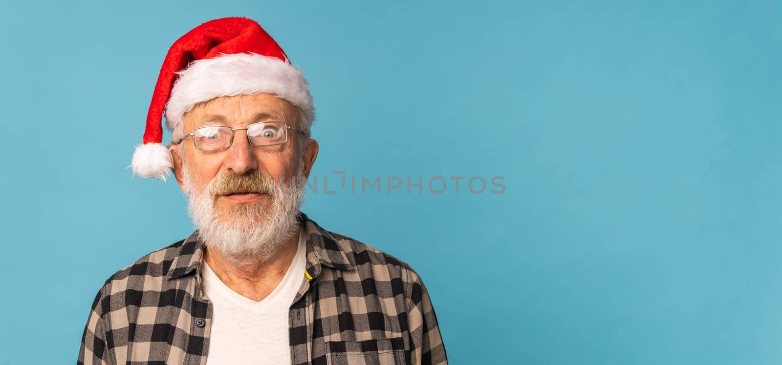 Portrait of Surprised Santa Claus on blue background - emotions and winter holidays