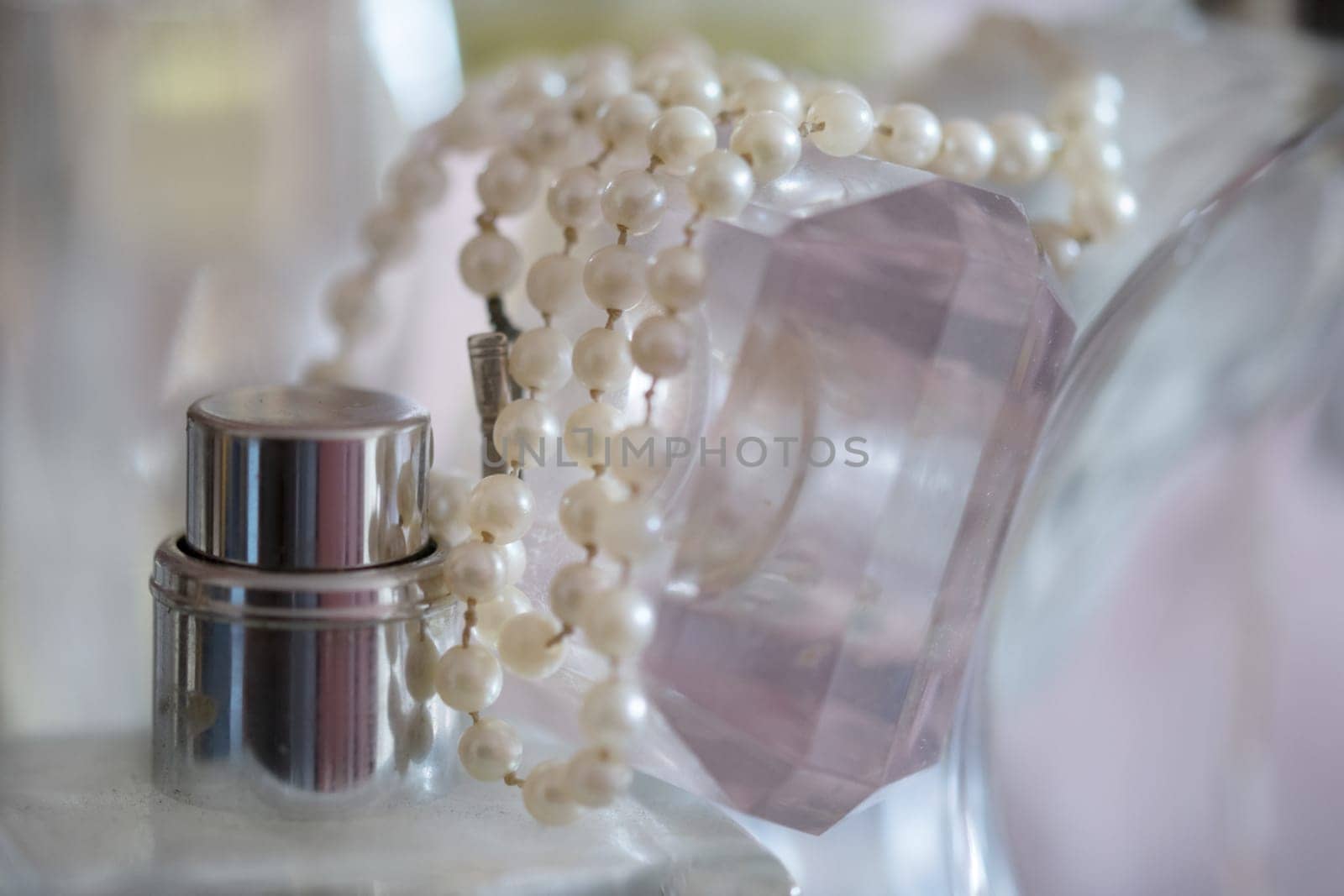 pearl necklace resting on perfume bottles