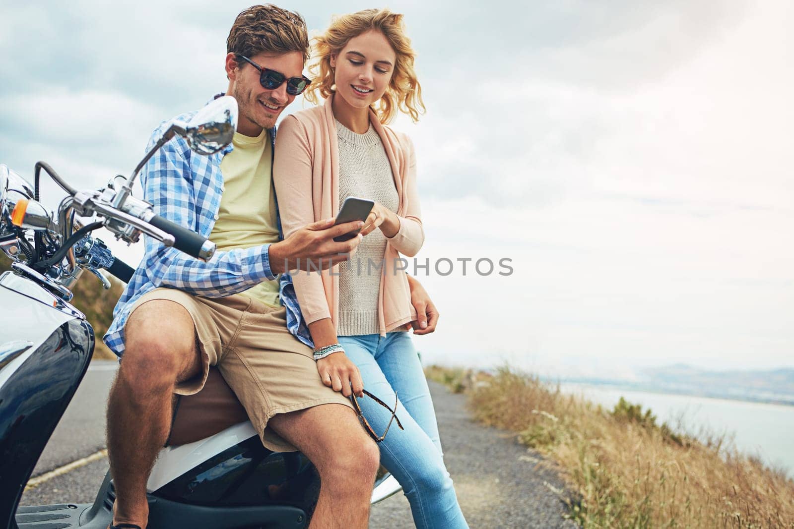 Lifes a journey...why travel alone. a couple using a cellphone while taking a break from their road trip