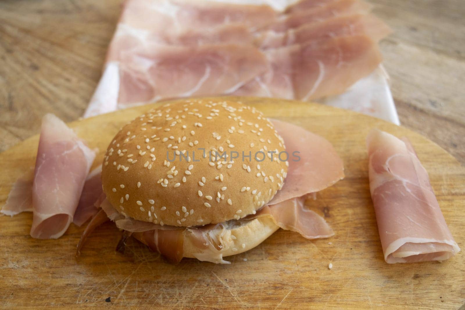 round sandwich with sesame seeds filled with raw ham