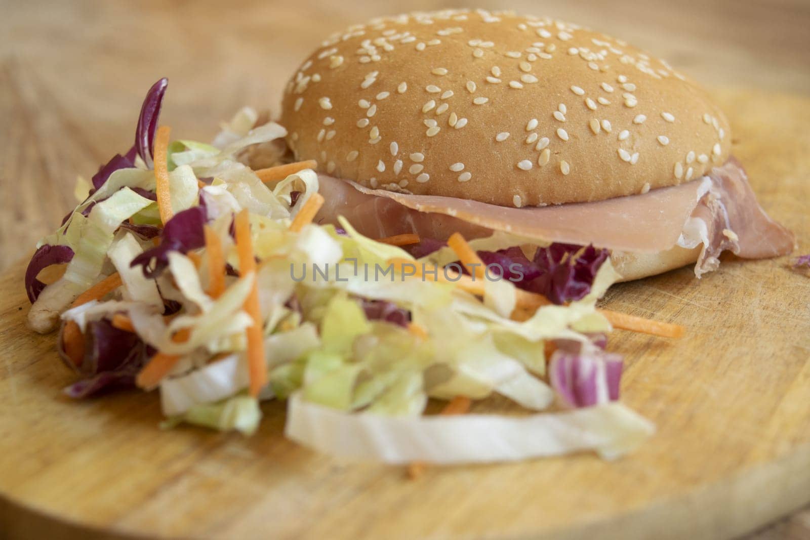 round sandwich filled with salad and raw ham