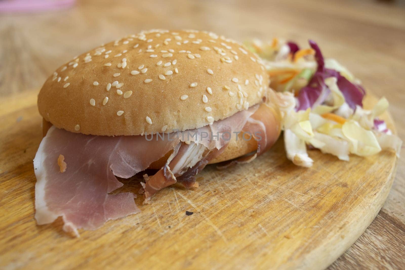 round sandwich filled with salad and raw ham