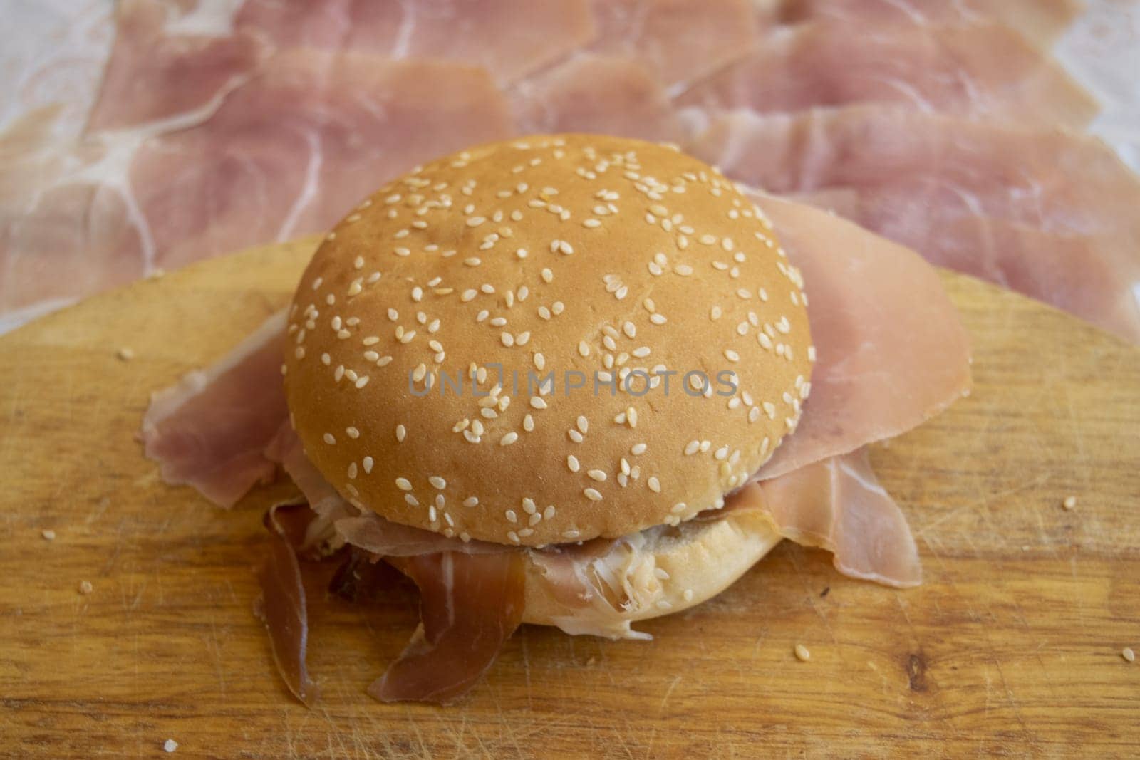 round sandwich with sesame seeds filled with raw ham