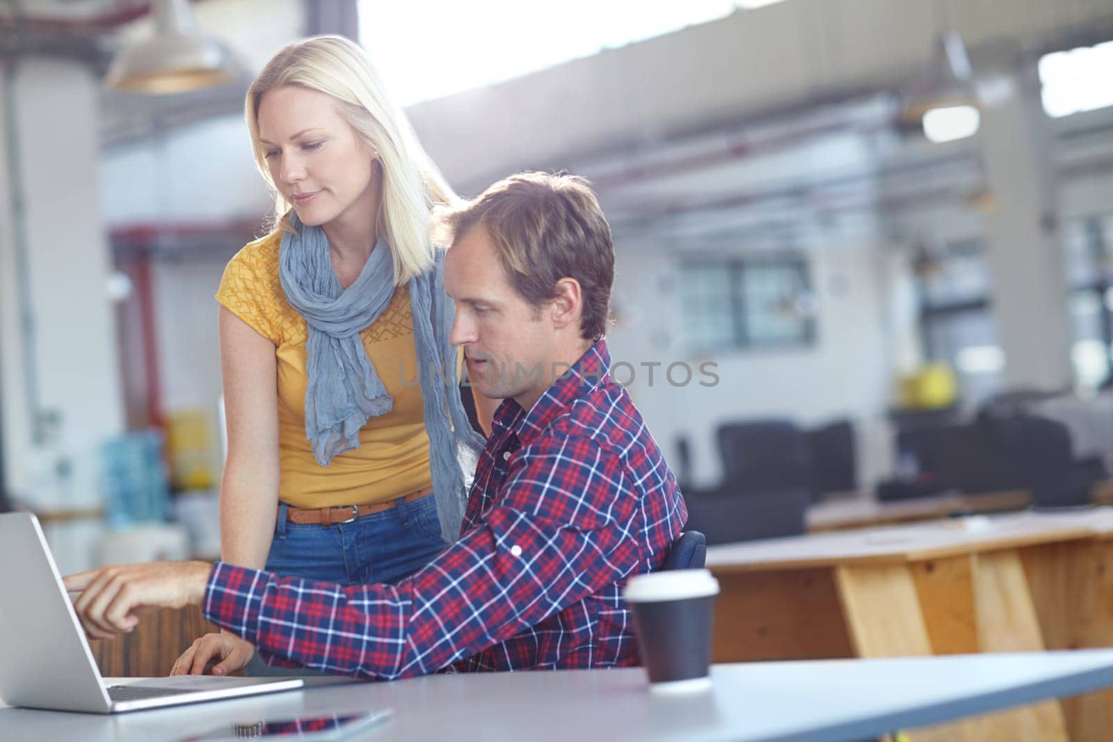 Theyve got technology on their side. two designers working on a laptop in an office. by YuriArcurs