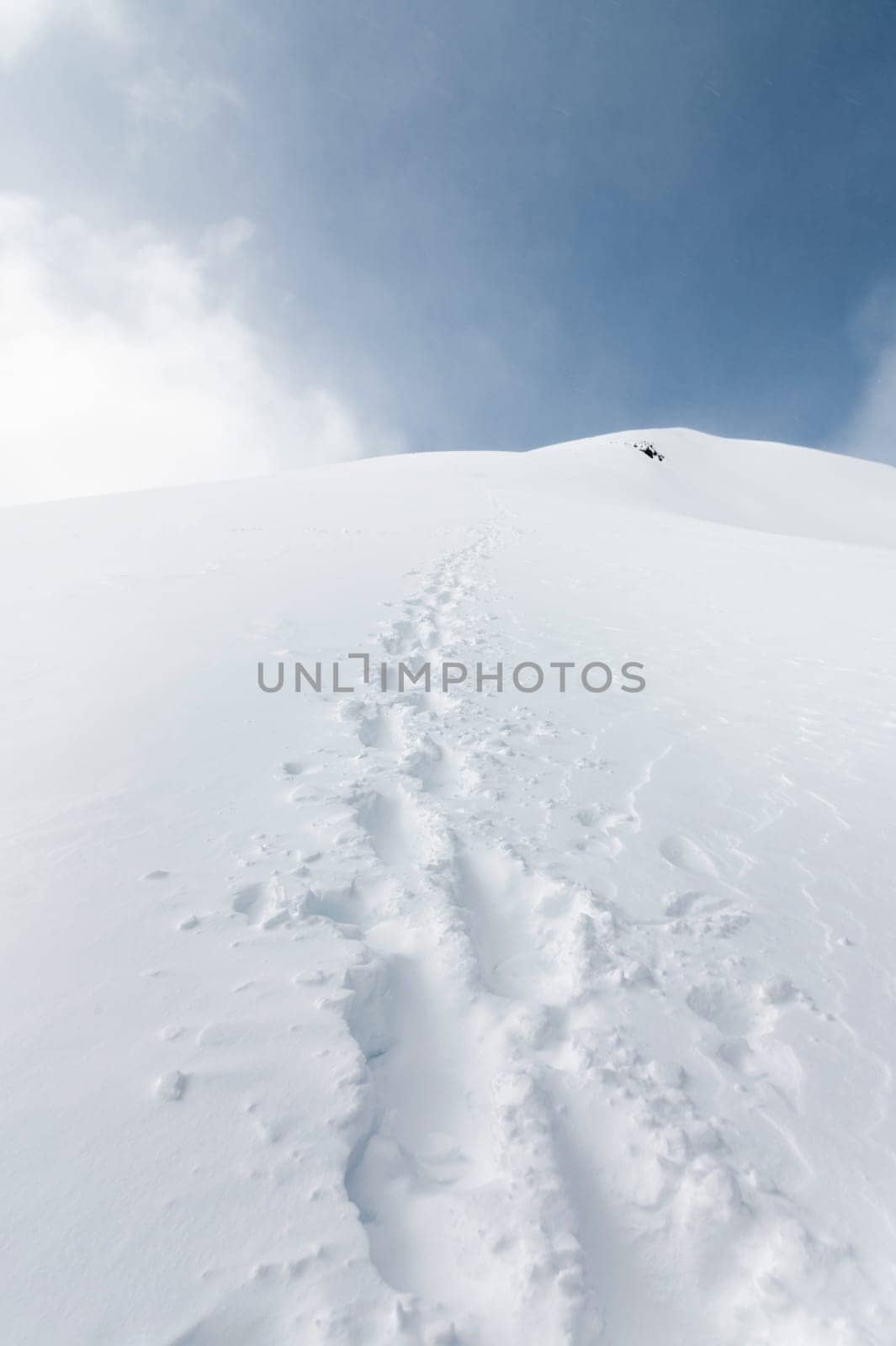 Landscape of snowy mountains with footprint on the snow during daytime in cloudy weather.