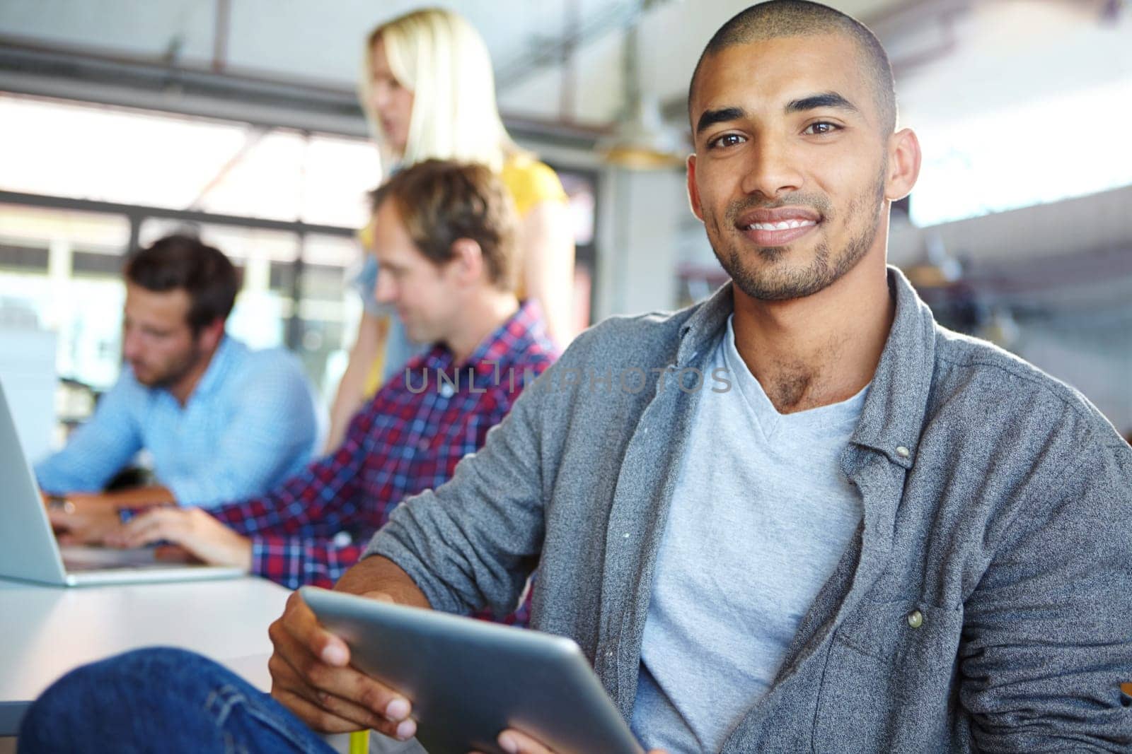 Bringing bright optimism to the workplace. Portrait of a designer using a digital tablet with colleagues in the background