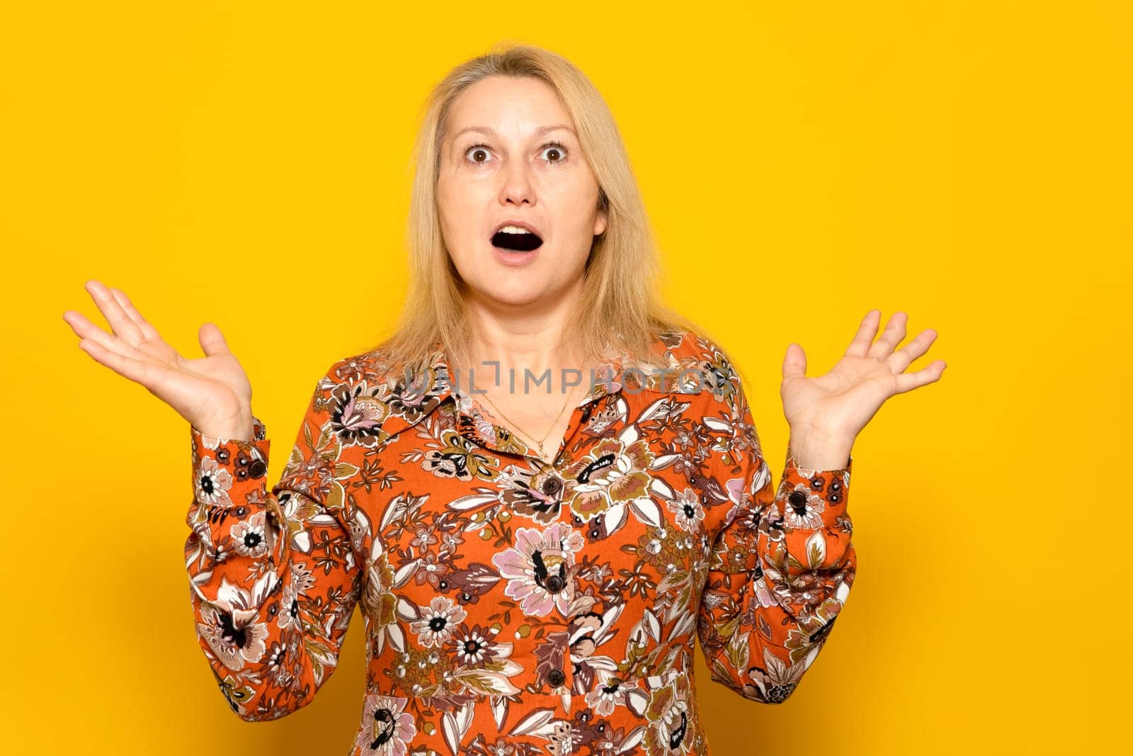 Surprised happy beauty woman looking at camera with open mouth with excitement. Expressive facial expressions. Beautiful woman acts as a satisfied excited product. Isolated on yellow background