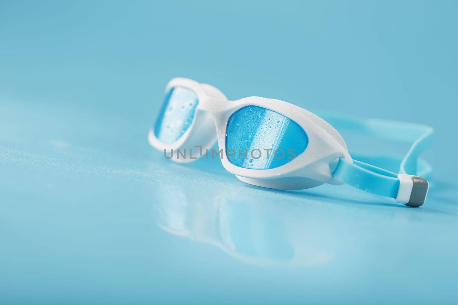 Swimming goggles in a white frame with on a blue background by AlexGrec