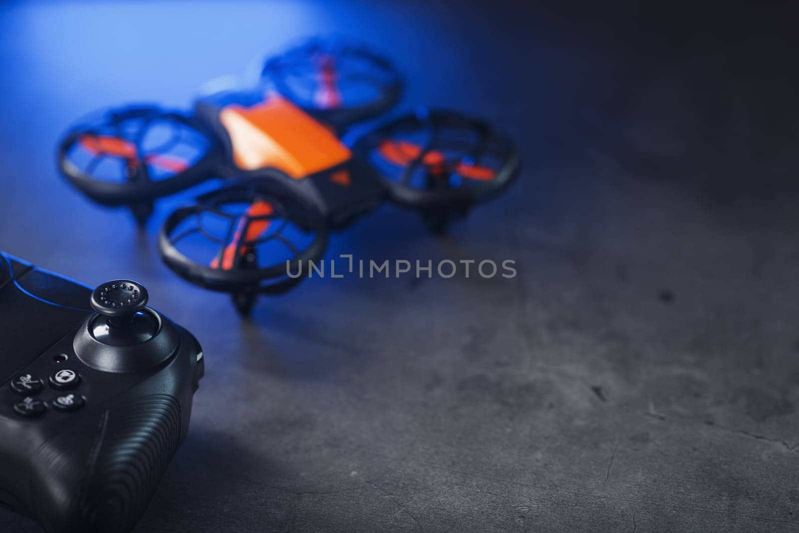 Gaming orange mini drone on a dark background for control from a gamepad