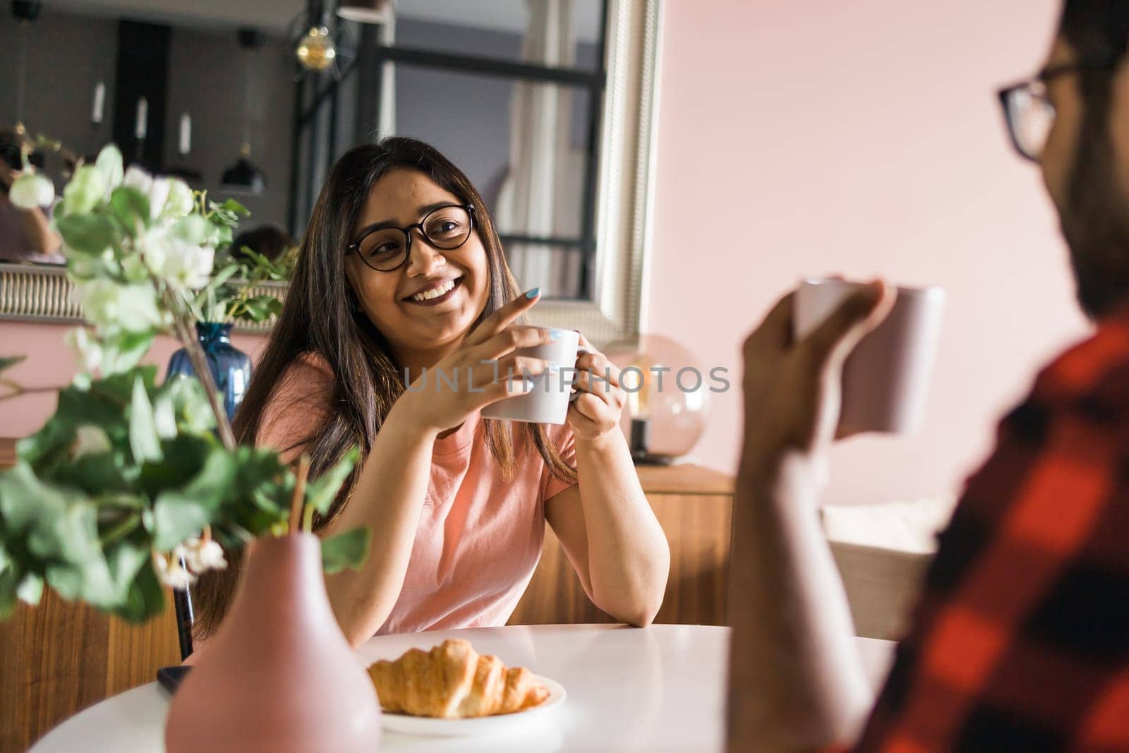 Young diverse loving couple eating croissant and talks together at home in breakfast time. Communication and relationship