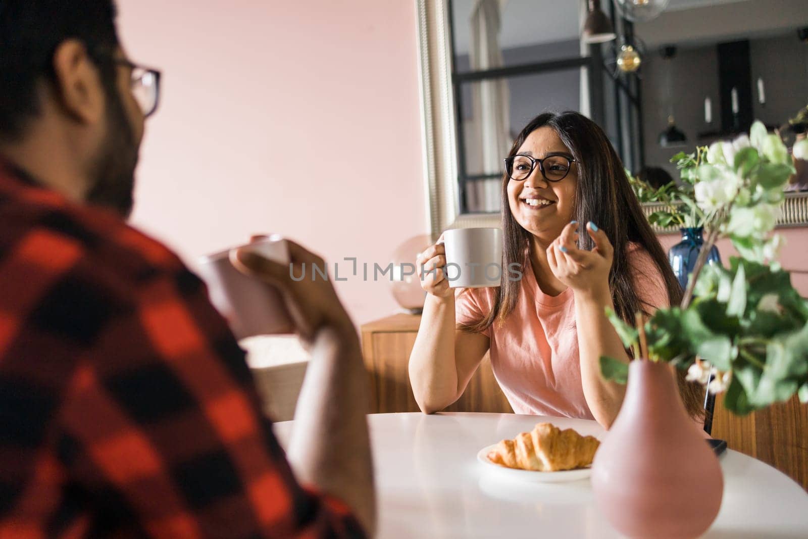 Young diverse loving couple eating croissant and talks together at home in breakfast time. Communication and relationship concept by Satura86