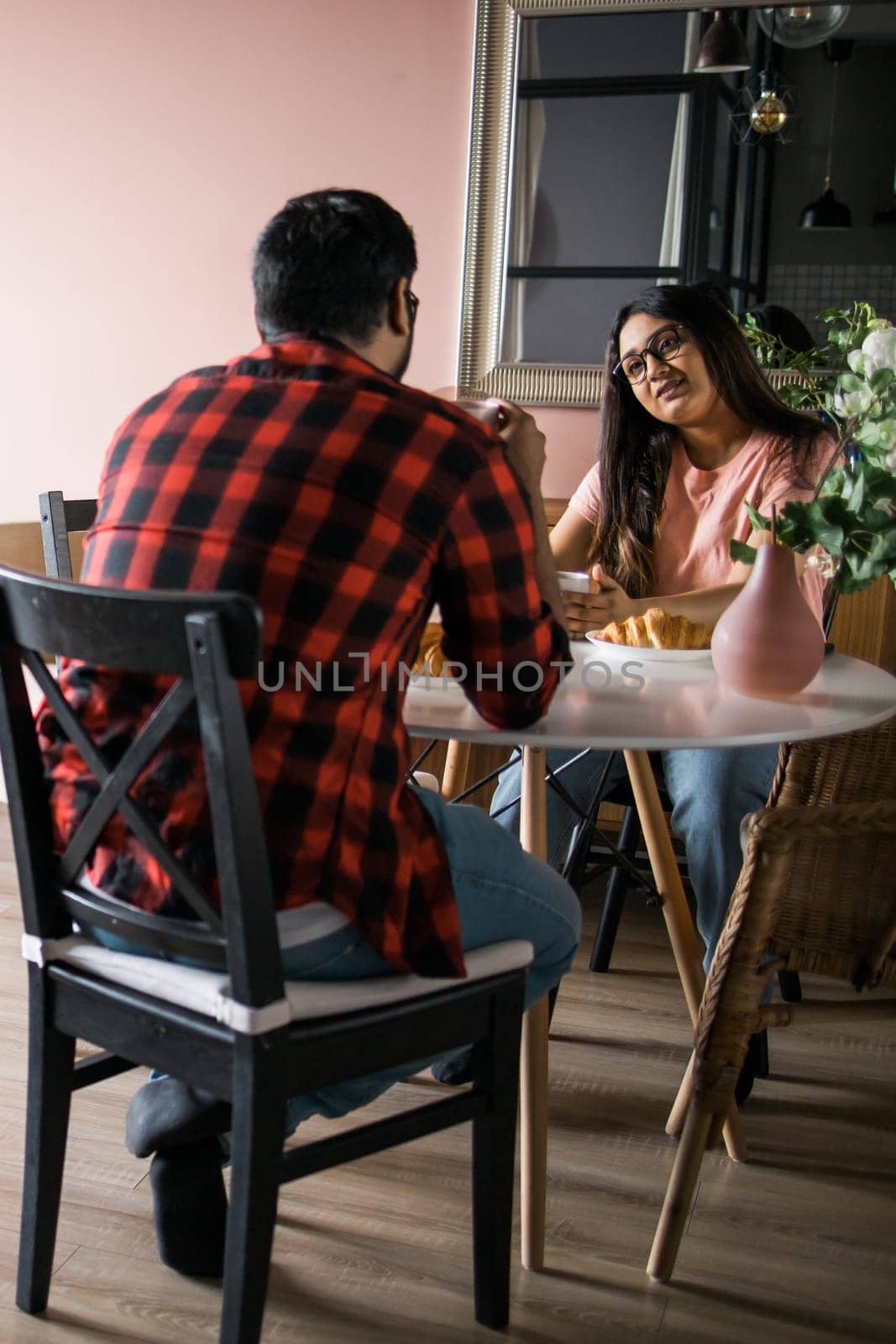 Happy indian couple having breakfast and small talk together in kitchen - friendship, dating and family