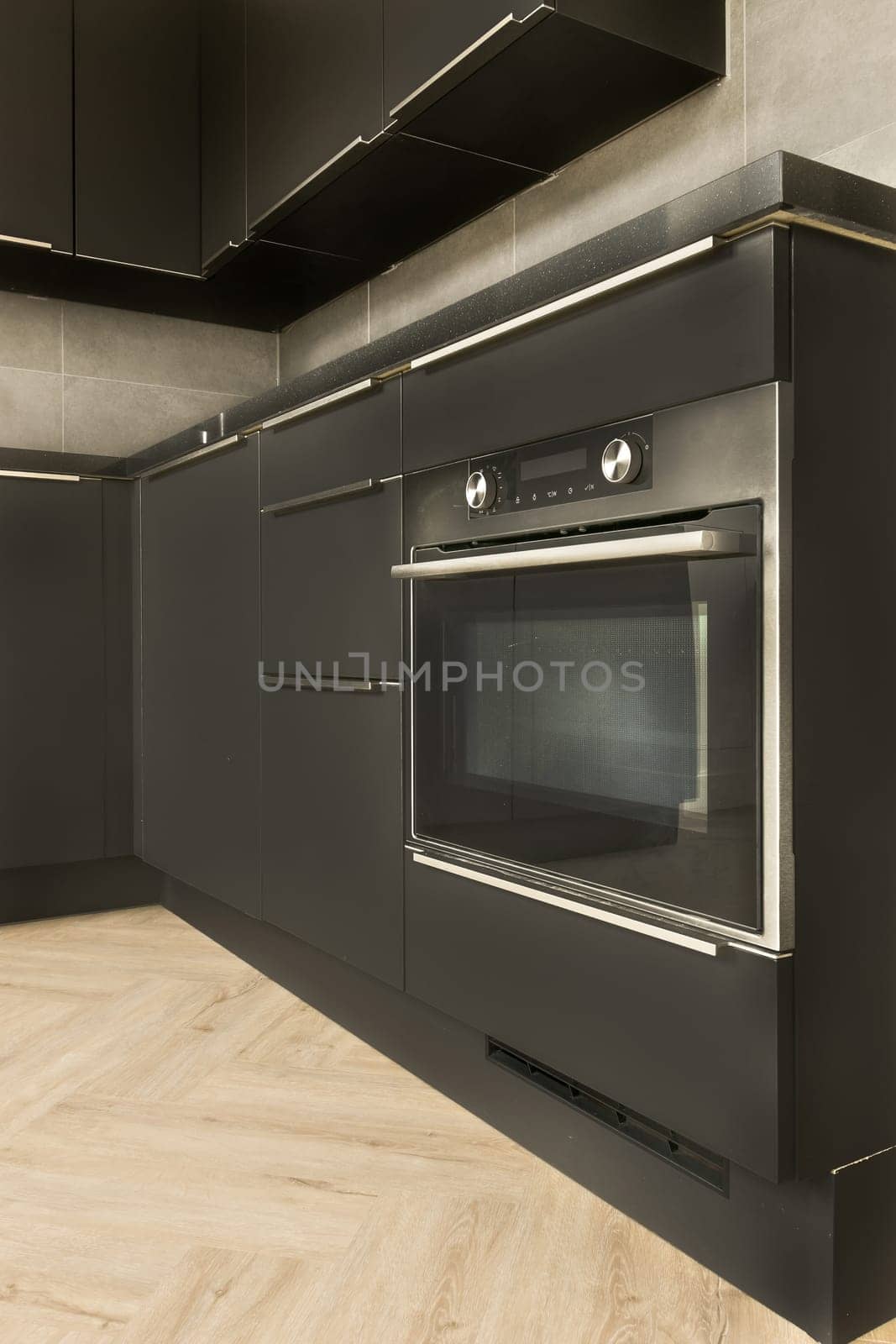 a modern kitchen with wood flooring and an oven on the wall in the center of the space is empty