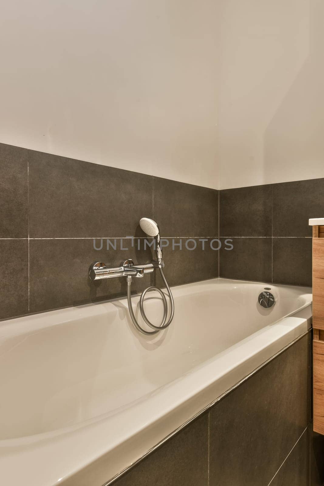 a modern bathroom with grey tiles and white fixtures on the walls, along with a wooden cabinet in the corner