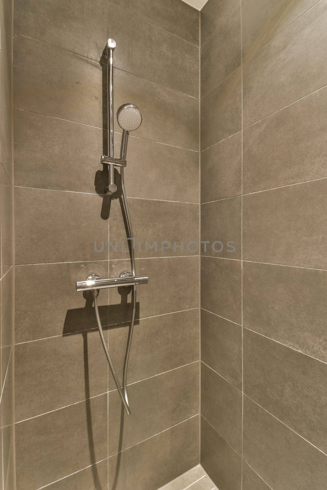 a shower with a removable shower head in a bathroom by casamedia