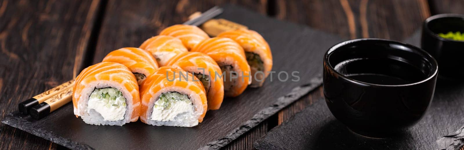 Banner Sushi roll philadelphia with salmon and cucumber and cream cheese on black background close-up. Sushi menu. Japanese food concept by Satura86