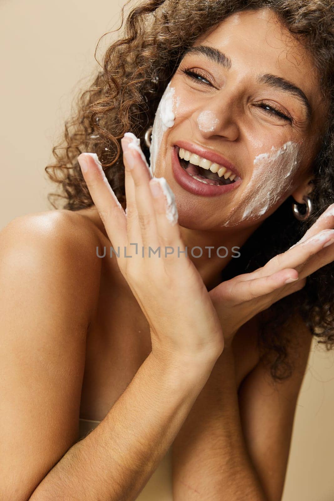 Woman beauty face close-up applying foam to wash and cleanse skin with fingers of her hand, nail and hair health, hair dryer style curly afro hair, body and beauty care concept. High quality photo