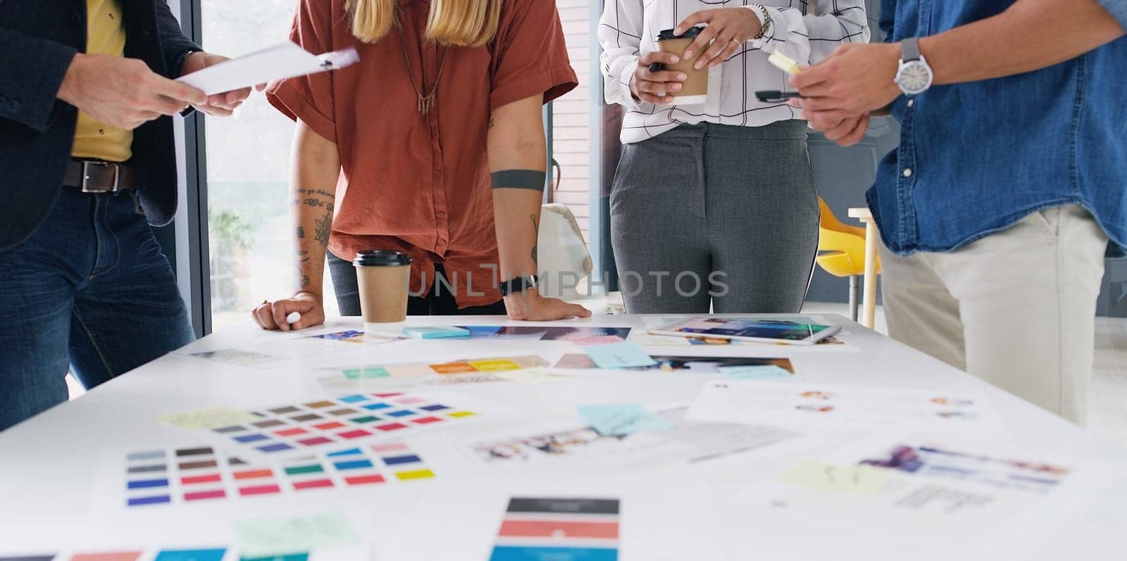 Taking the project from concept to completion. Closeup shot of a group of designers going through paperwork together in an office. by YuriArcurs