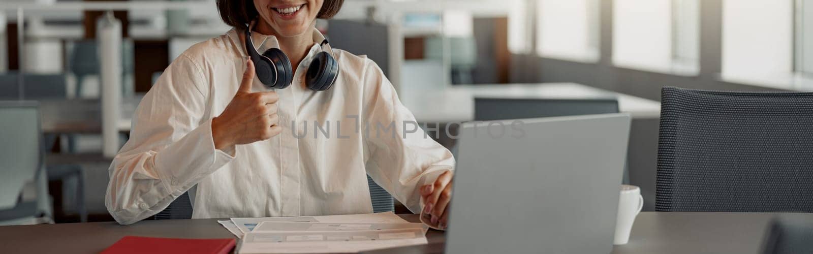 Attractive european business woman working laptop while sitting in cozy cafe and showing thumb up by Yaroslav_astakhov