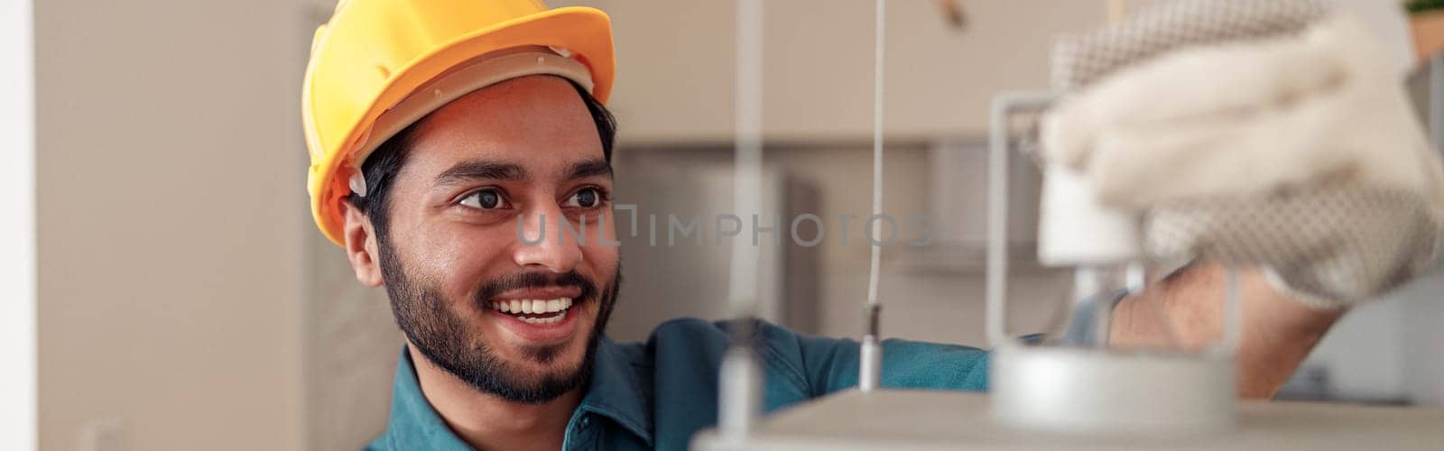 Smiling Electrician is installing the light bulbs into the chandelier at home. High quality photo