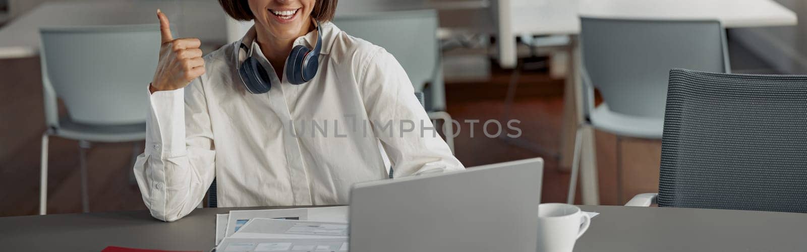 Attractive european business woman working laptop while sitting in cozy cafe and showing thumb up by Yaroslav_astakhov