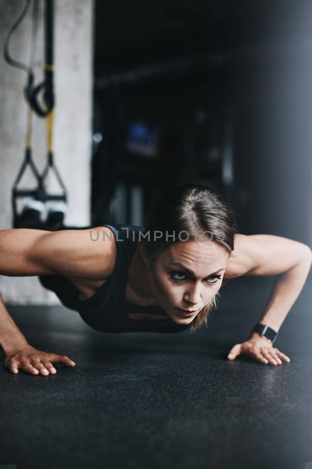 Fit is a lifestyle choice. an attractive young woman doing push ups in a gym. by YuriArcurs