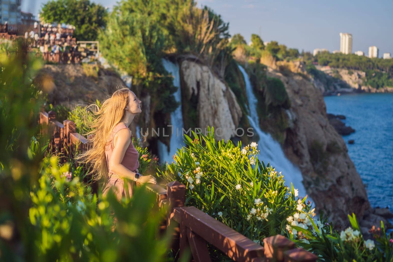 Beautiful woman with long hair on the background of Duden waterfall in Antalya. Famous places of Turkey. Lower Duden Falls drop off a rocky cliff falling from about 40 m into the Mediterranean Sea in amazing water clouds. Tourism and travel destination photo in Antalya, Turkey. Turkiye.
