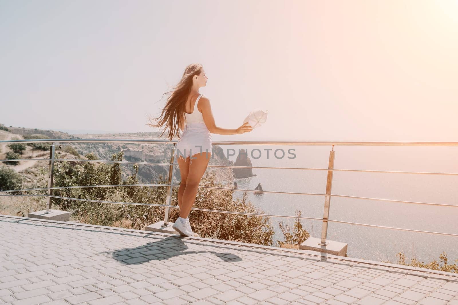 Woman summer travel sea. Happy tourist enjoy taking picture outdoors for memories. Woman traveler posing over sea bay surrounded by volcanic mountains, sharing travel adventure journey by panophotograph