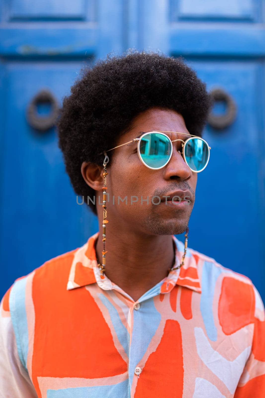 Vertical portrait of young confident and cool black man wearing sunglasses outdoors. Lifestyle concept.
