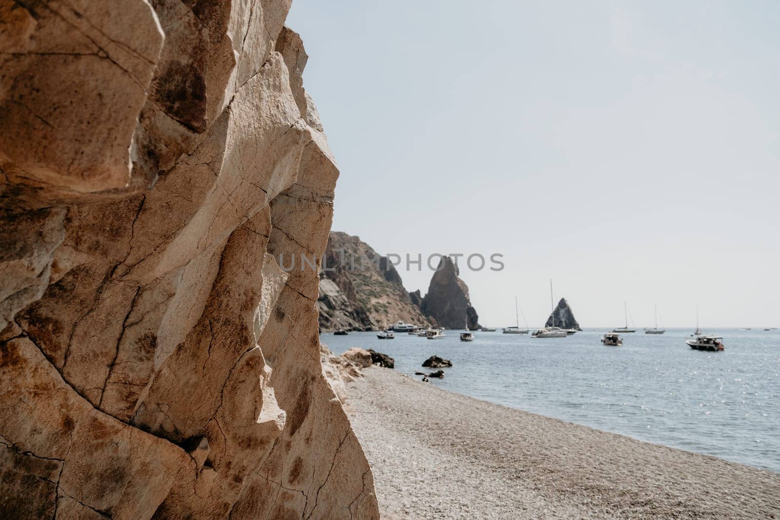 calm azure sea and volcanic rocky shores. Small waves on water surface in motion blur. Nature summer ocean sea beach background. Nobody. Holiday, vacation and travel concept by panophotograph