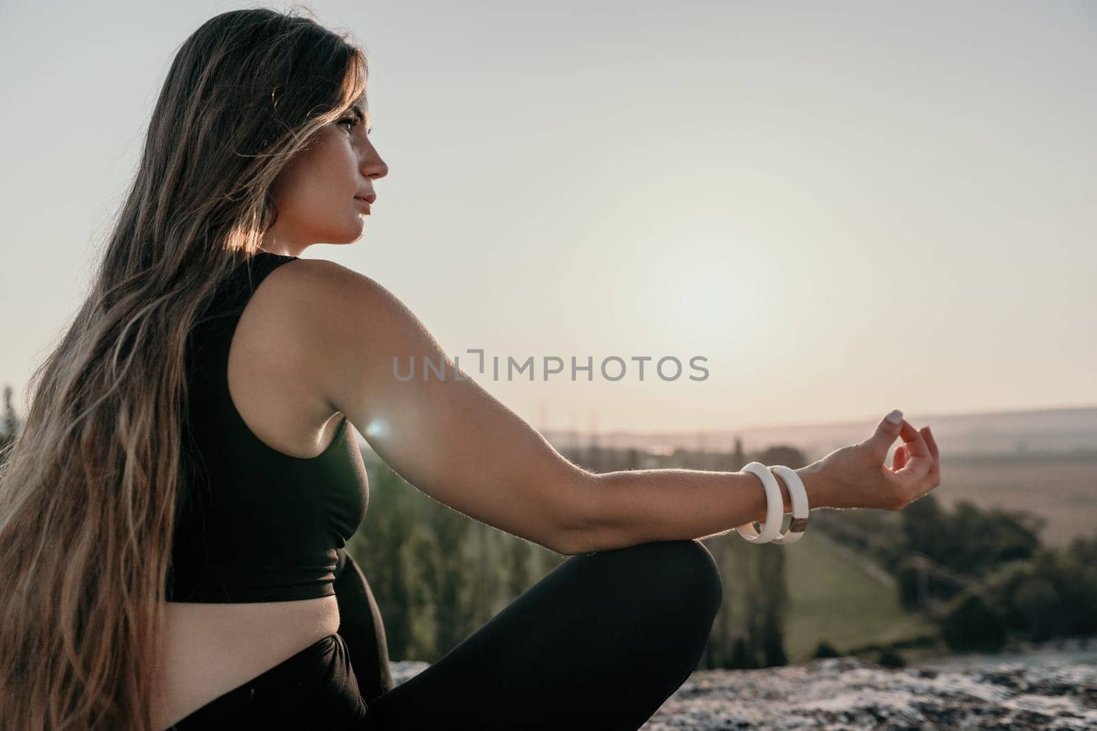 Fitness woman. Well looking middle aged woman with long hair, fitness instructor in leggings and tops doing stretching and pilates on the rock near forest. Female fitness yoga routine concept. by panophotograph