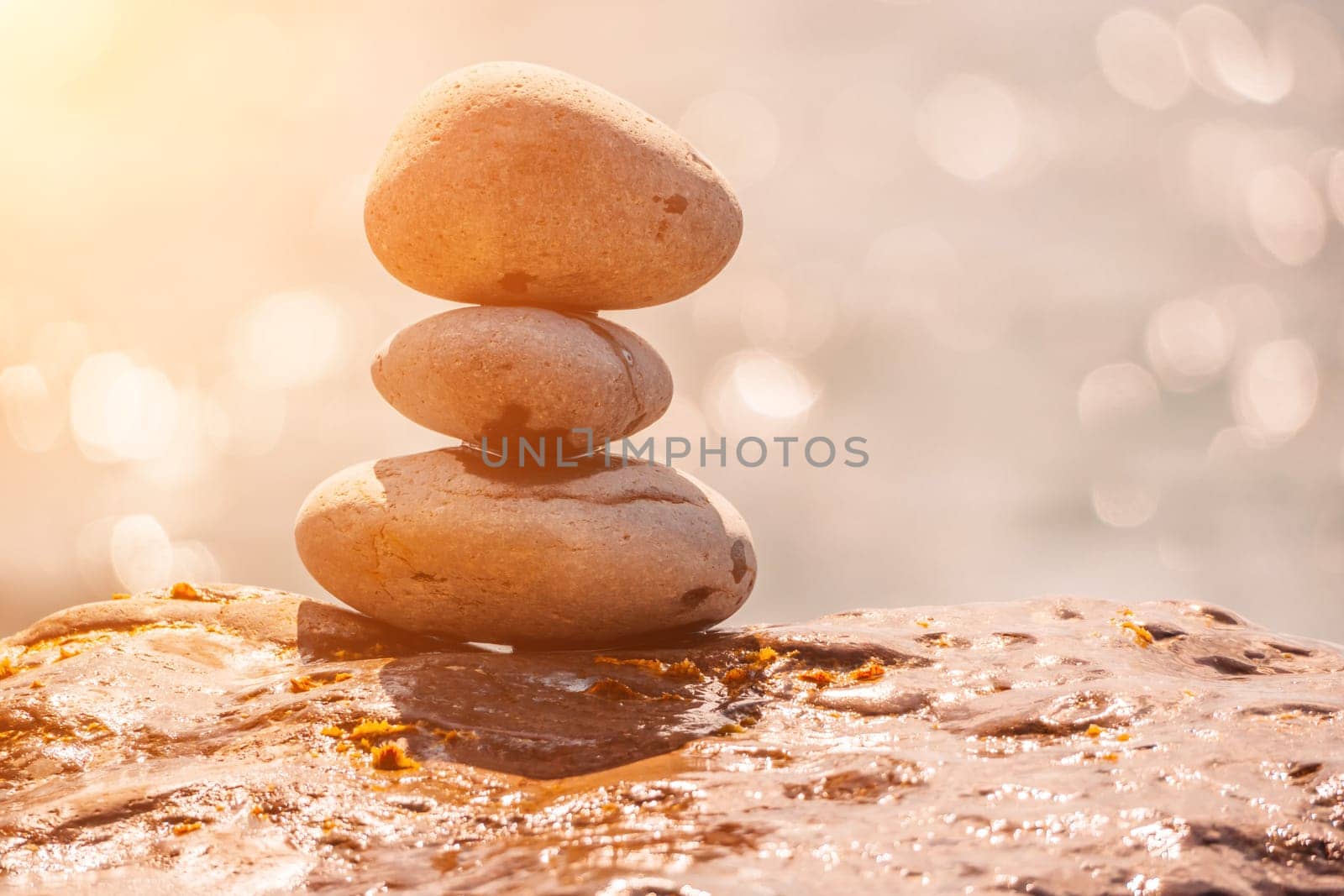 Balanced Pebbles Pyramid on the Beach on Sunny Day and Clear Sky at Sunset. Blue Sea on Background Selective focus, zen stones on sea beach, meditation, spa, harmony, calm, balance concept.
