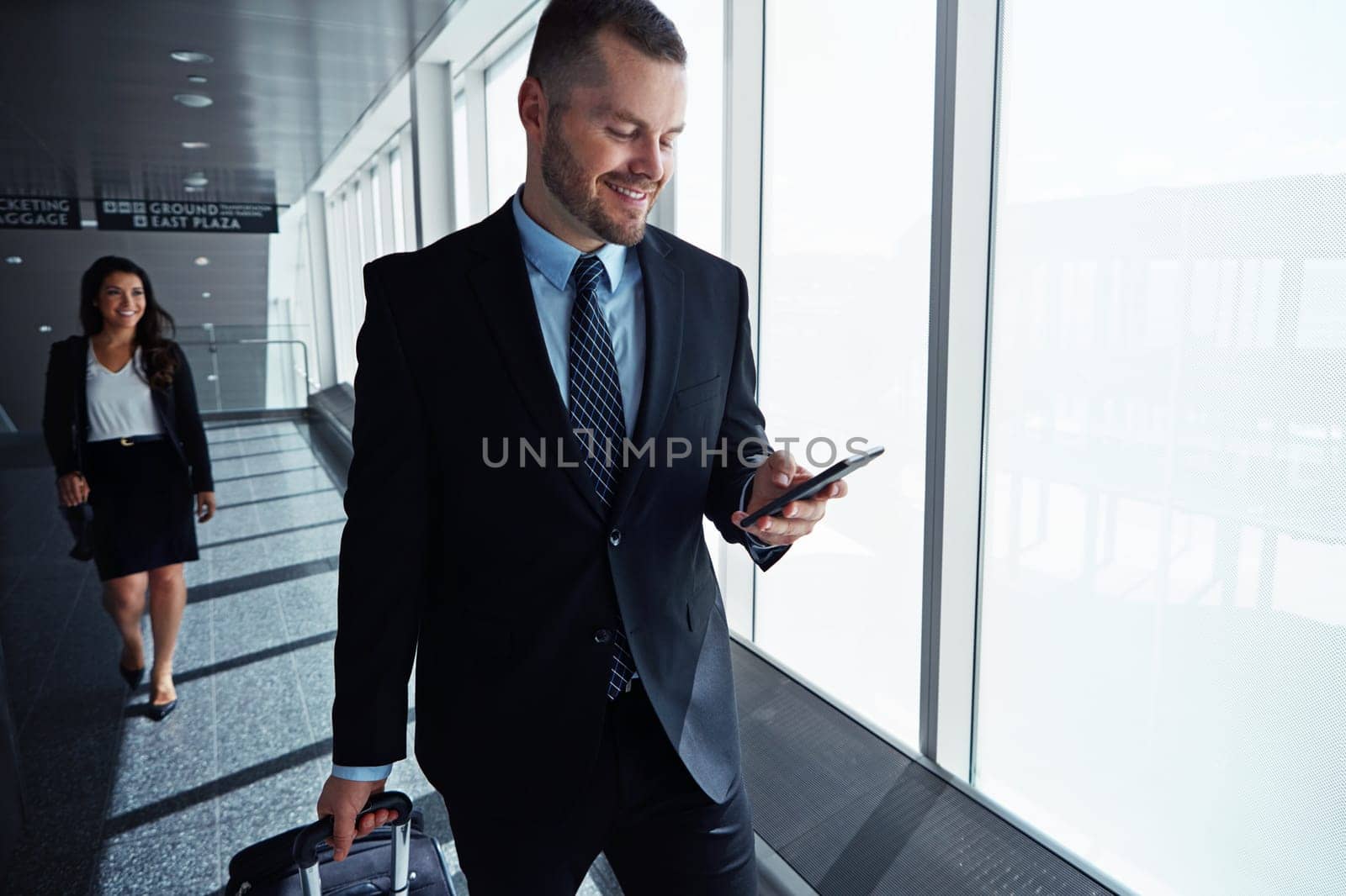 Arranging business travel has never been easier. two executive businesspeople walking through an airport during a business trip