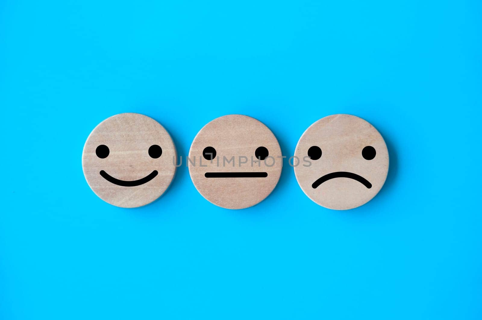 Happy, neutral, and sad emotion faces on wooden circle. Customer satisfaction and evaluation concept.