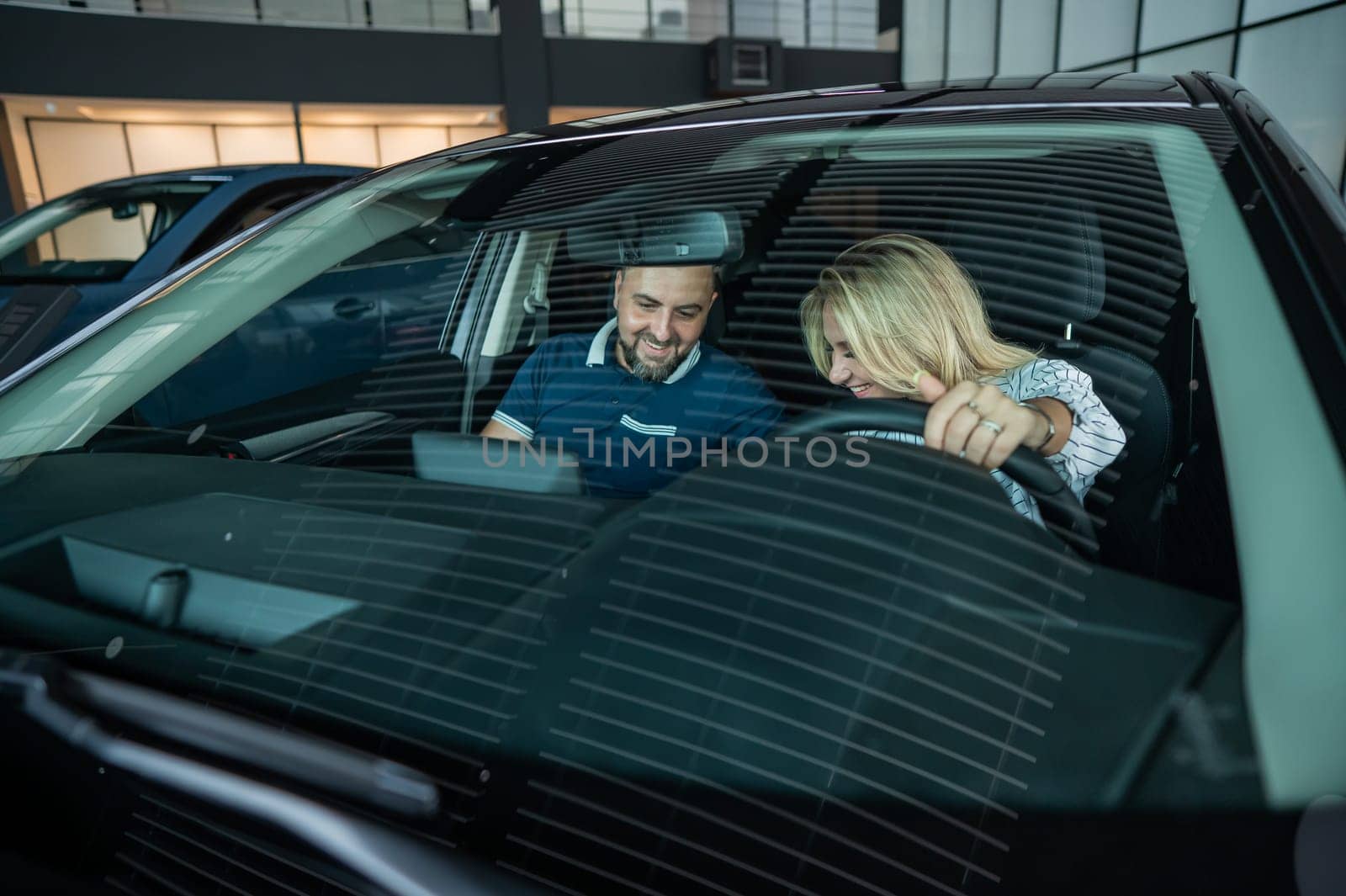 A happy caucasian couple is sitting in a new car and looking at the salon. by mrwed54