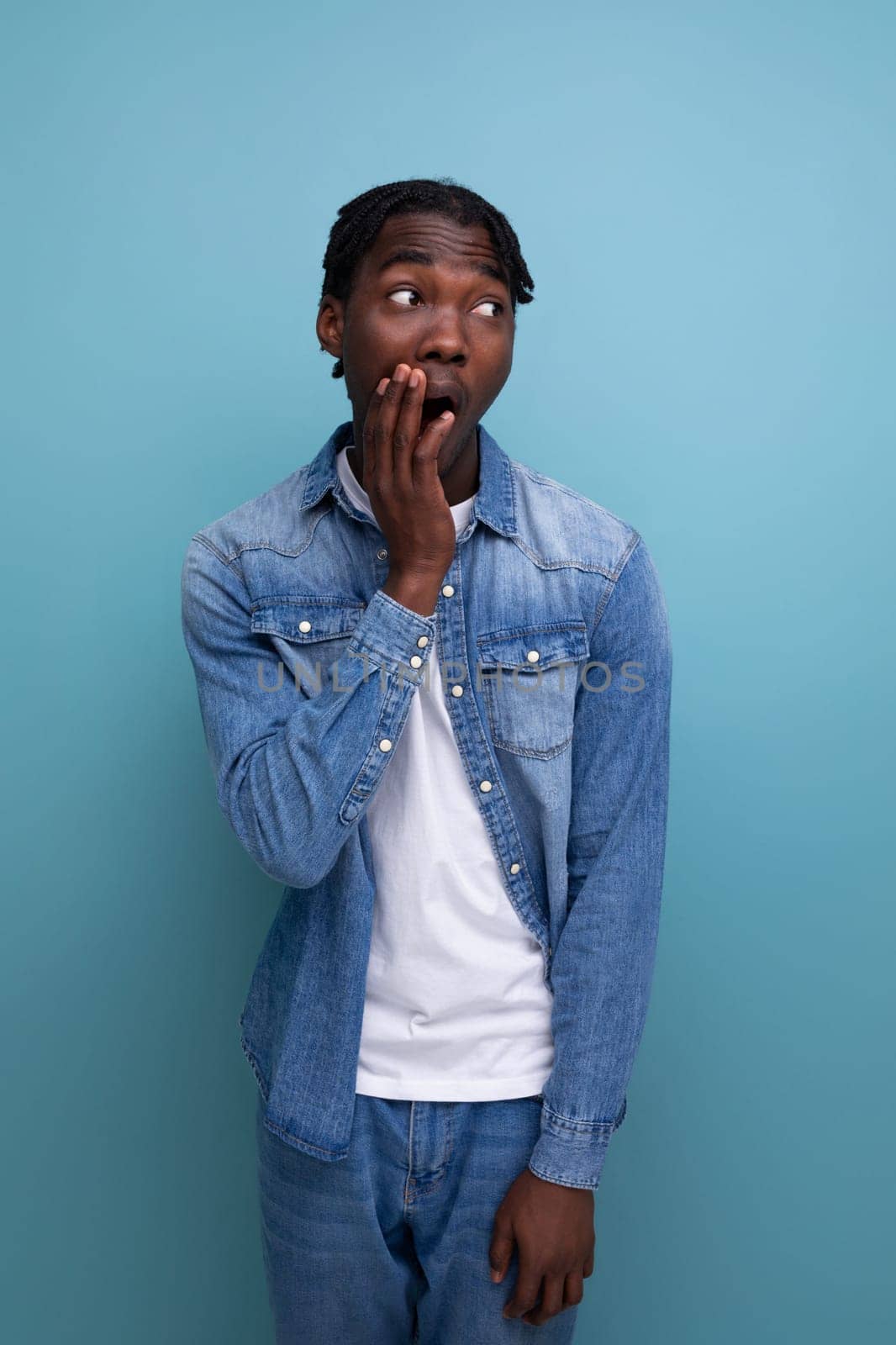 close-up portrait of a surprised young african guy with dreadlocks in a denim jacket.