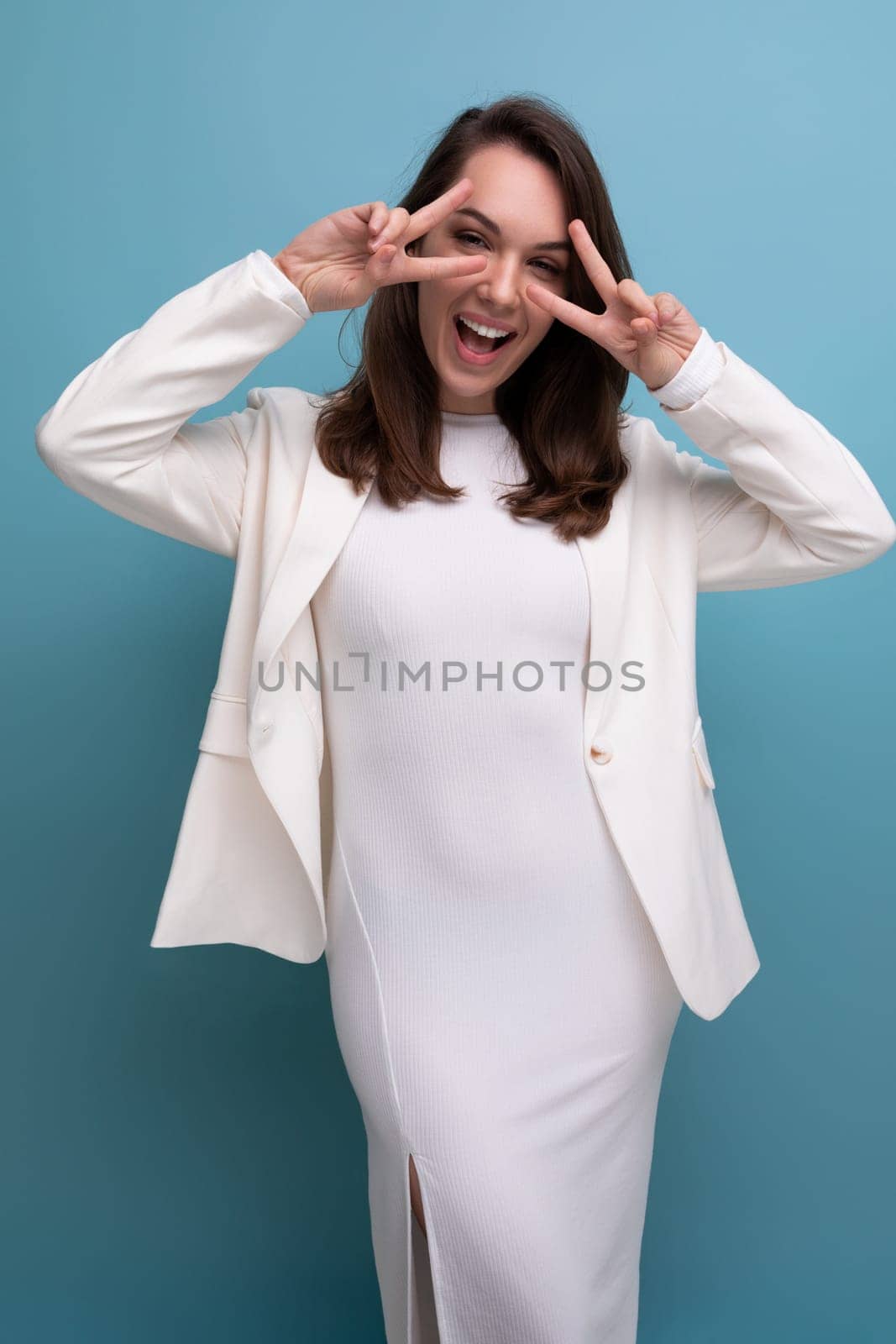european brunette woman in white dress makes a grimace on studio background.