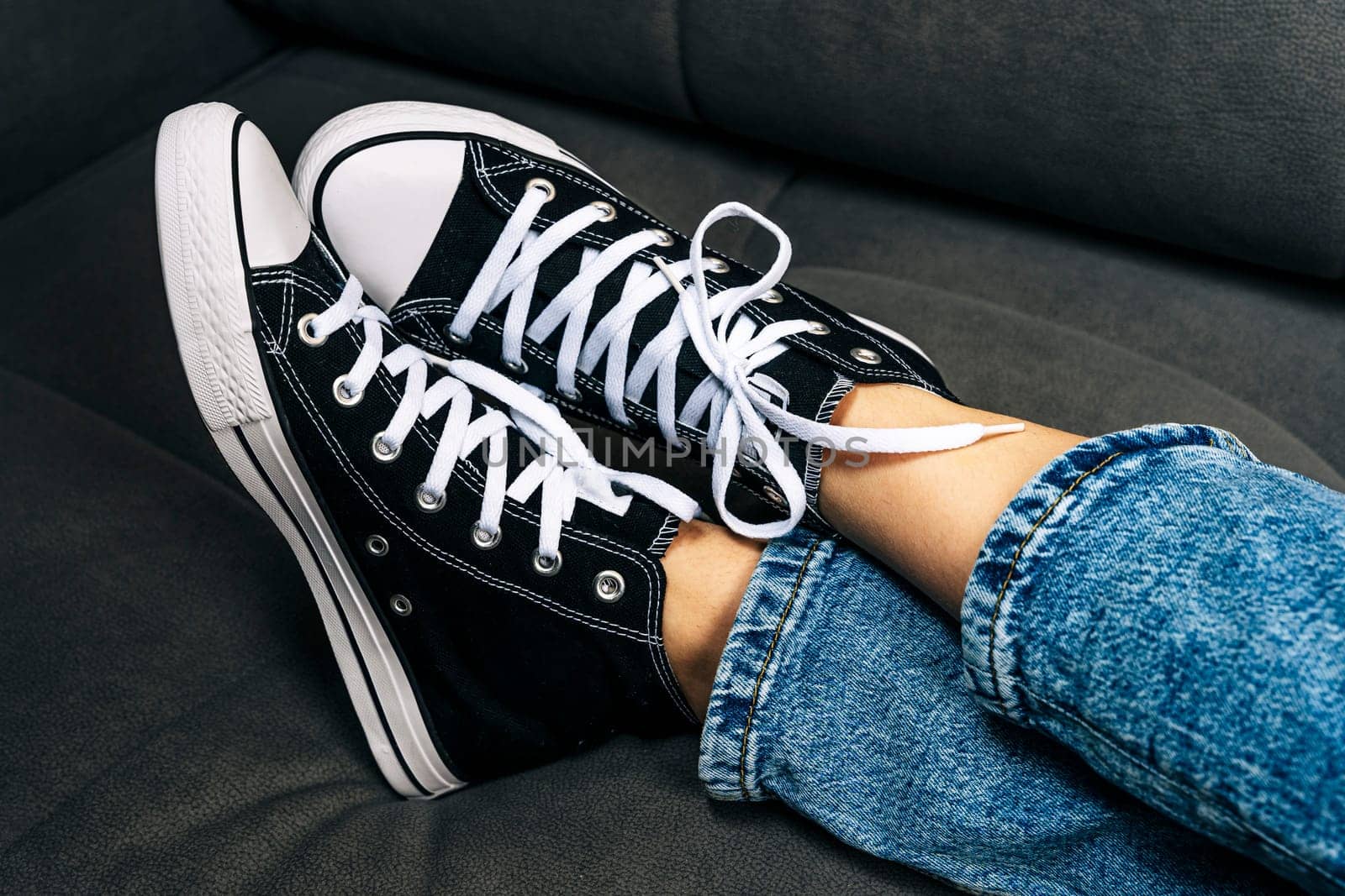 the girl's legs shod in classic sneakers. A sneakers on a girl's leg. Teenager's feet in casual new sneakers on the sofa close up image. Vintage style. concept image
