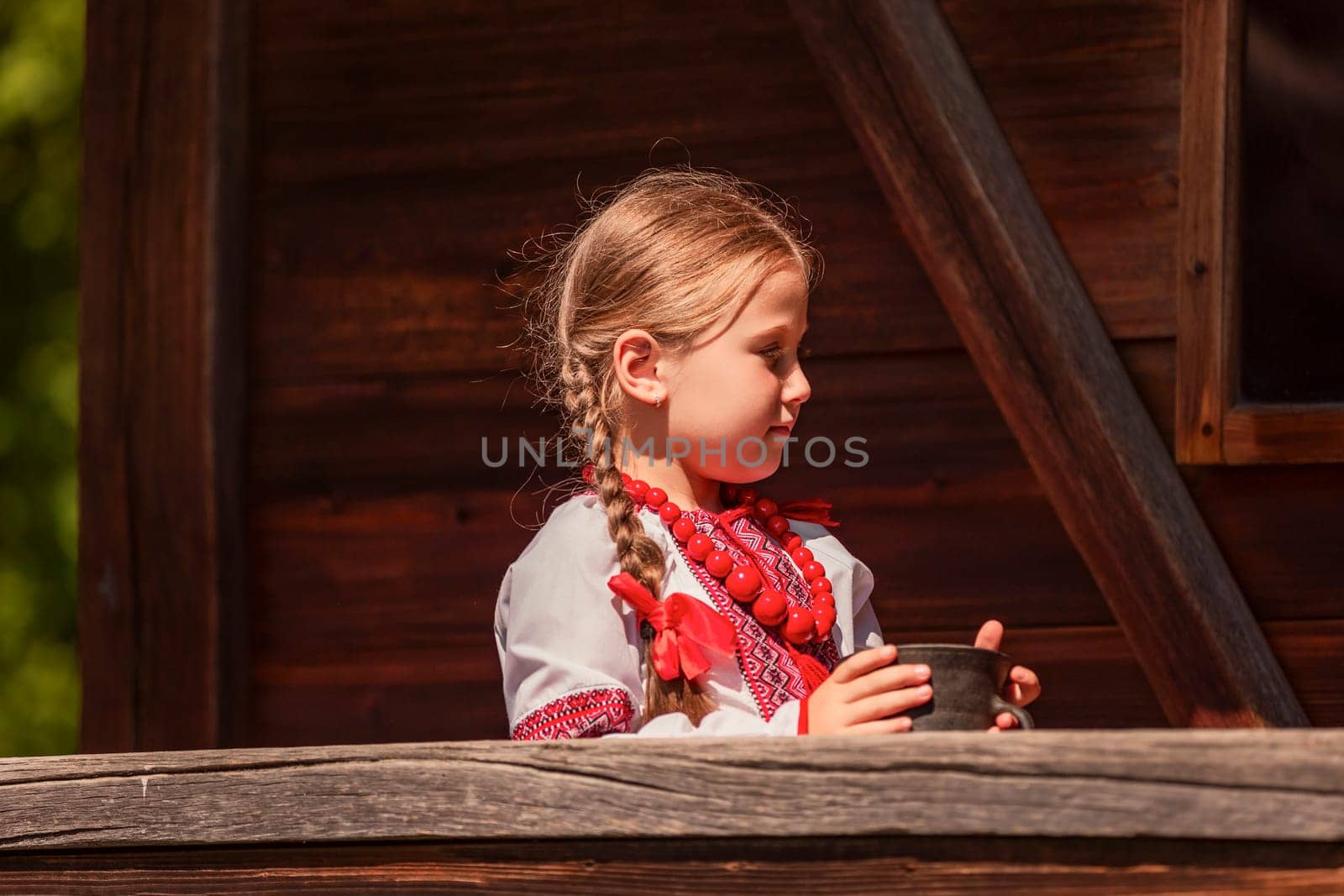 Girl in Ukrainian national dress with a jug outdoors