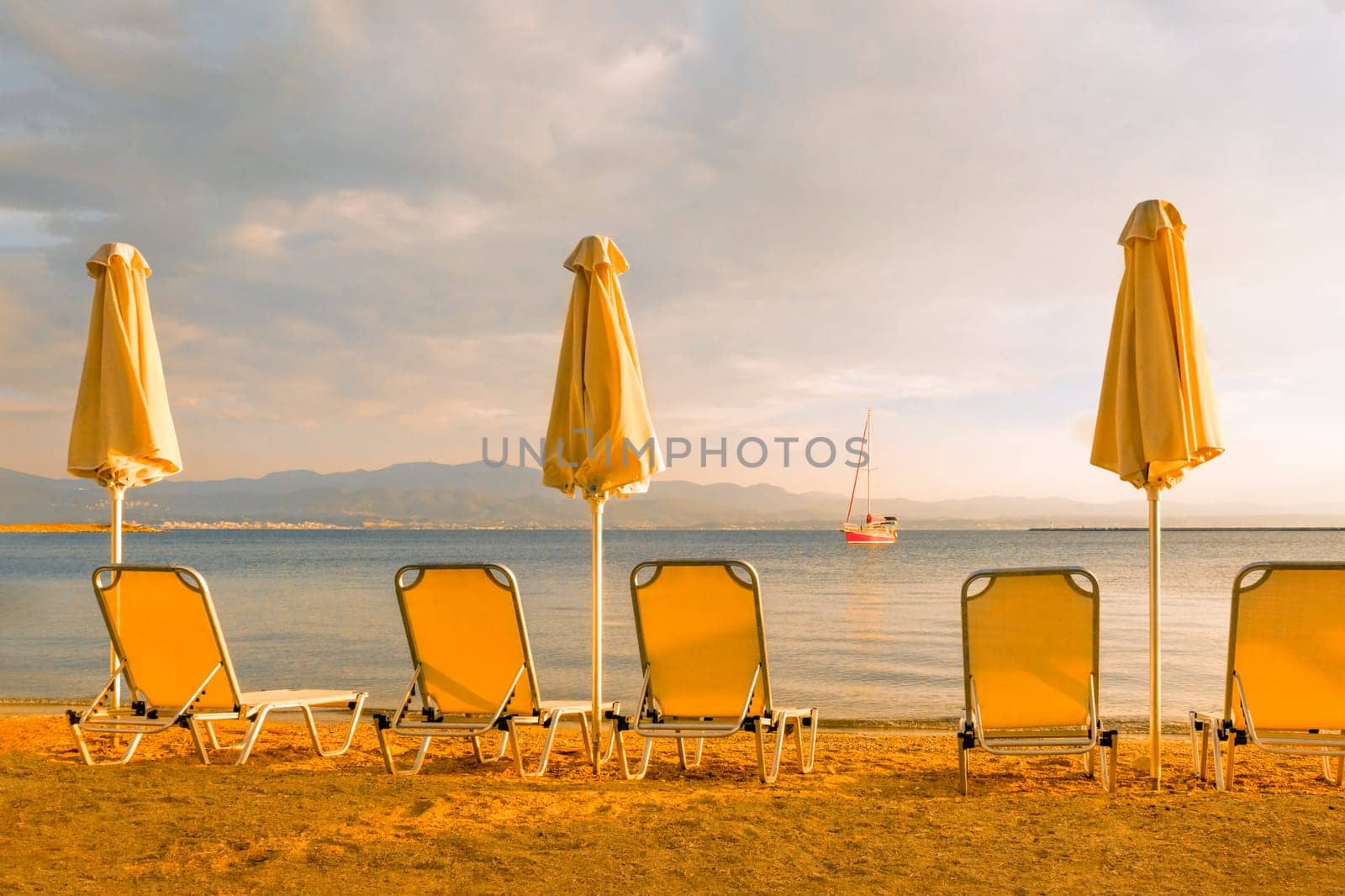 Empty beach chairs umbrella sun deck chairs beach lounge chair sea yacht beach sailboat sea shore sunset sail boat. Seashore background vacation sea travel sun parasol and chaise longue, chaise lounge by synel