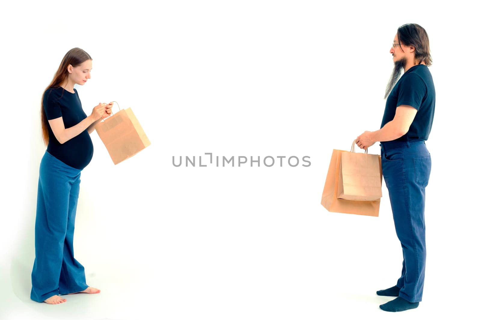 Portrait happy young pregnant woman and her husband with shopping bags and touching her big belly isolated on white background. Pregnancy shopping concept happy young family with shopping bags