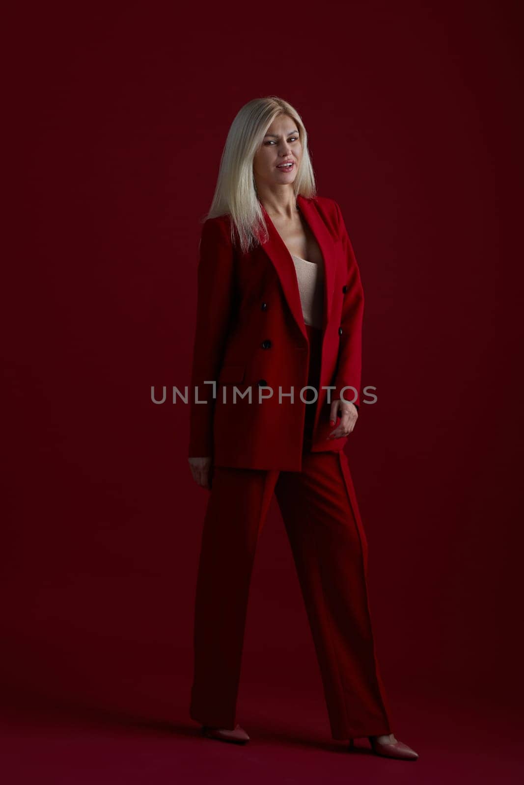 Portrait of a blonde woman in red dress on a red background