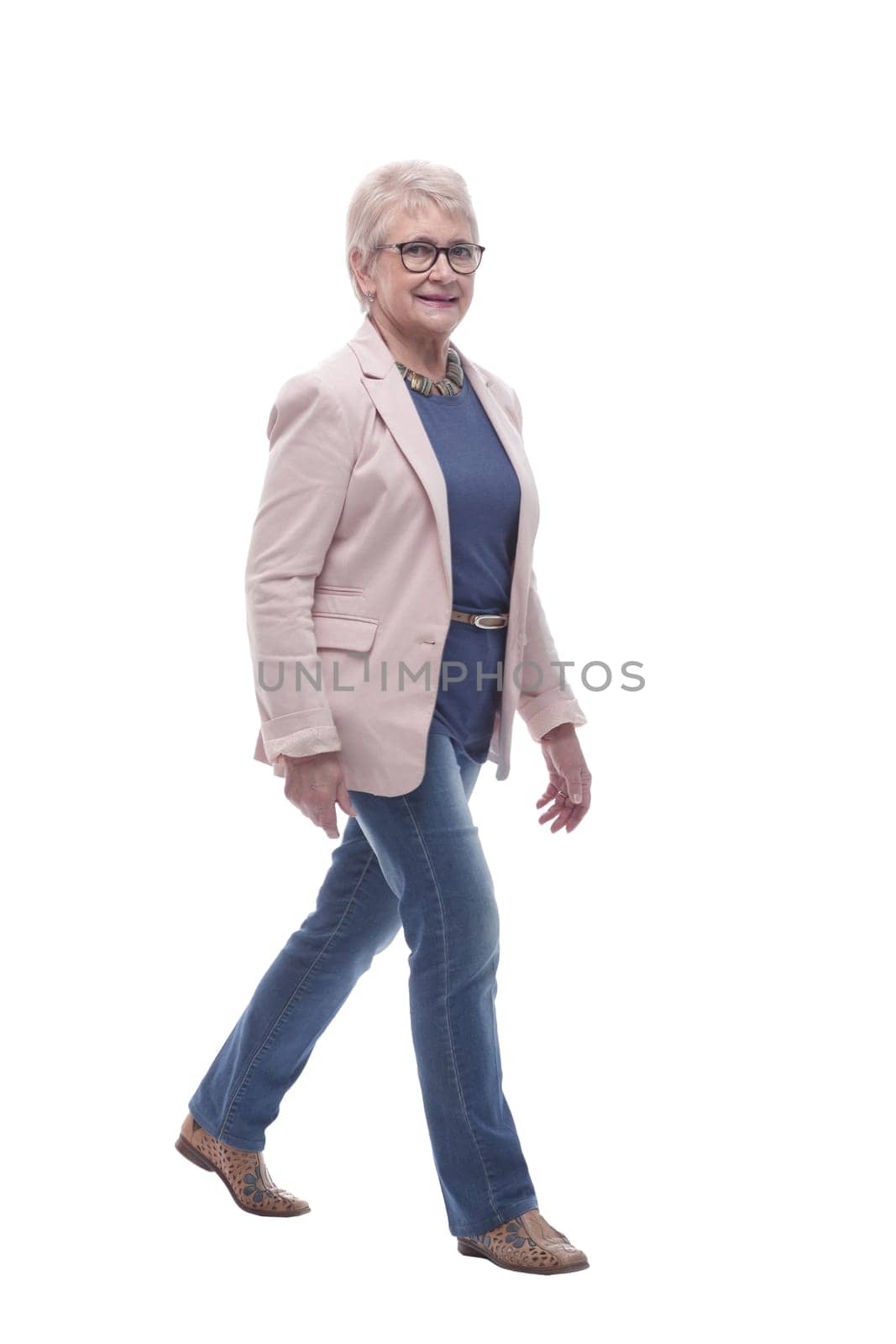 in full growth. confident senior woman goes forward . isolated on a white background