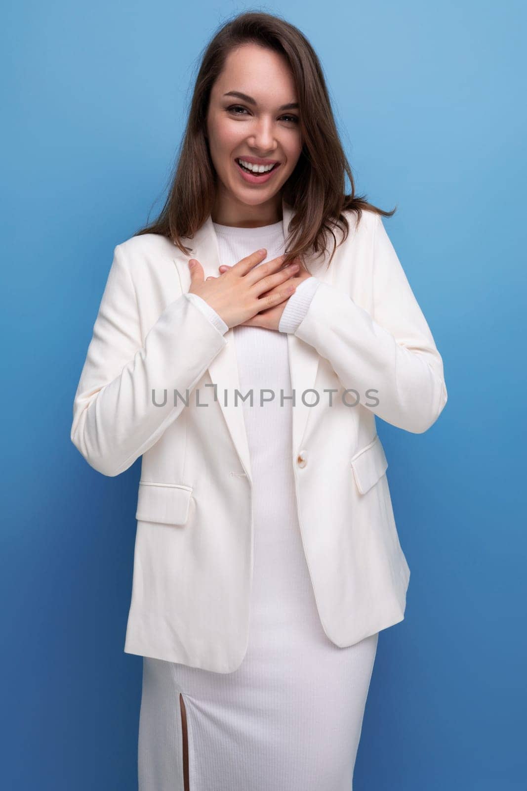 smiling well-groomed long-haired brunette business woman in white dress.