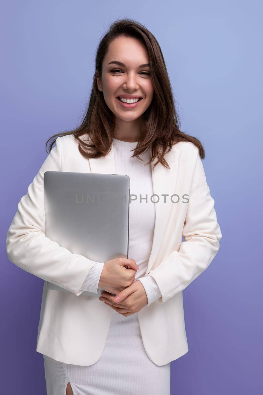 smiling brunette business women in white dress holding laptop for freelancing work.
