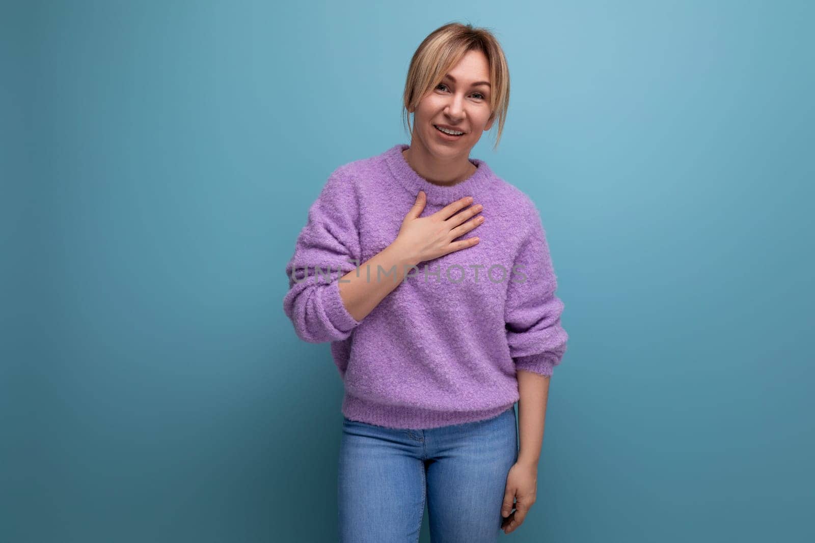 portrait of a joyful smiling blond young woman in a casual look with a kind heart and a strong character on a bright background with copy space.