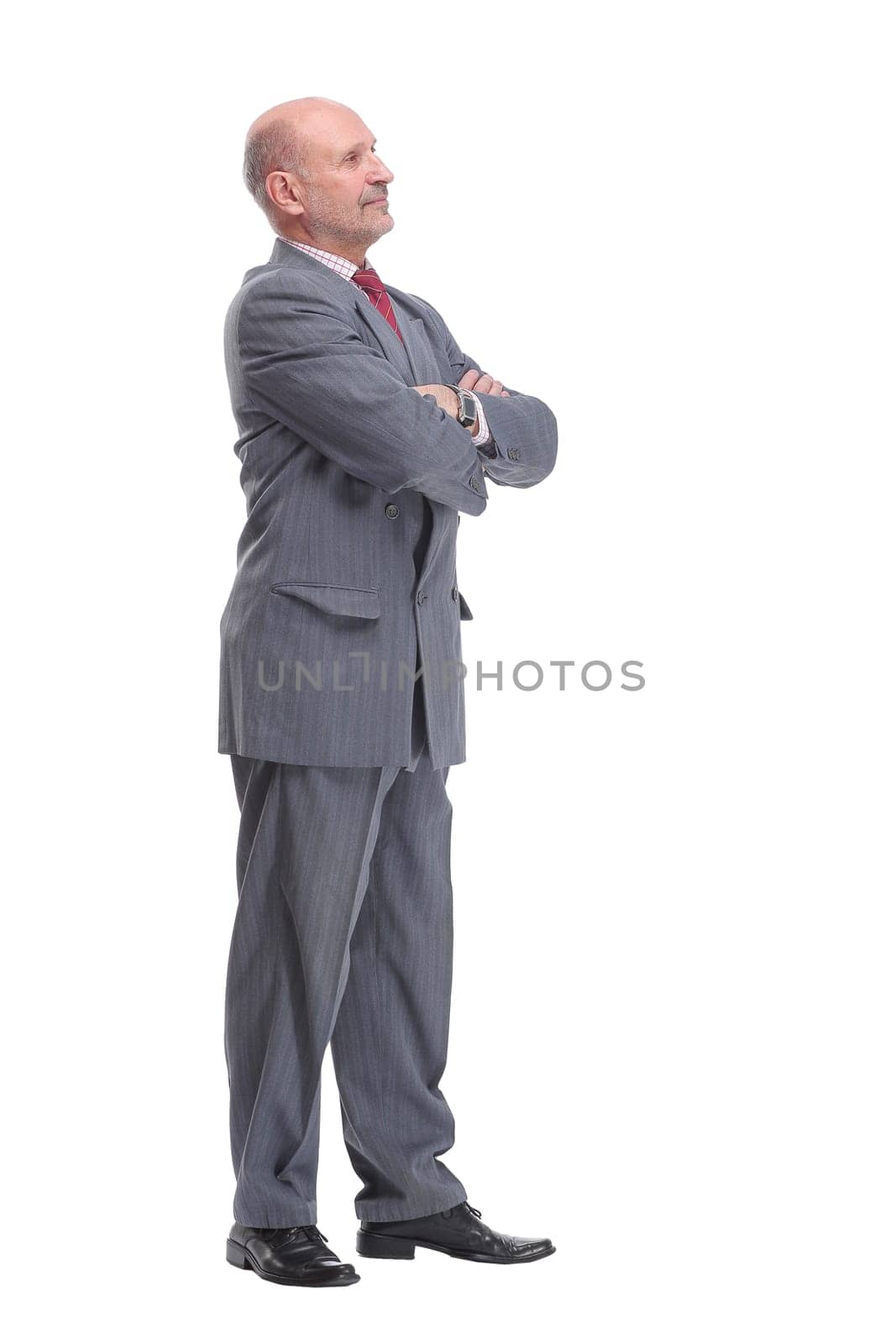 Full length profile portrait of businessman in suit looking at camera isolated on a white background.